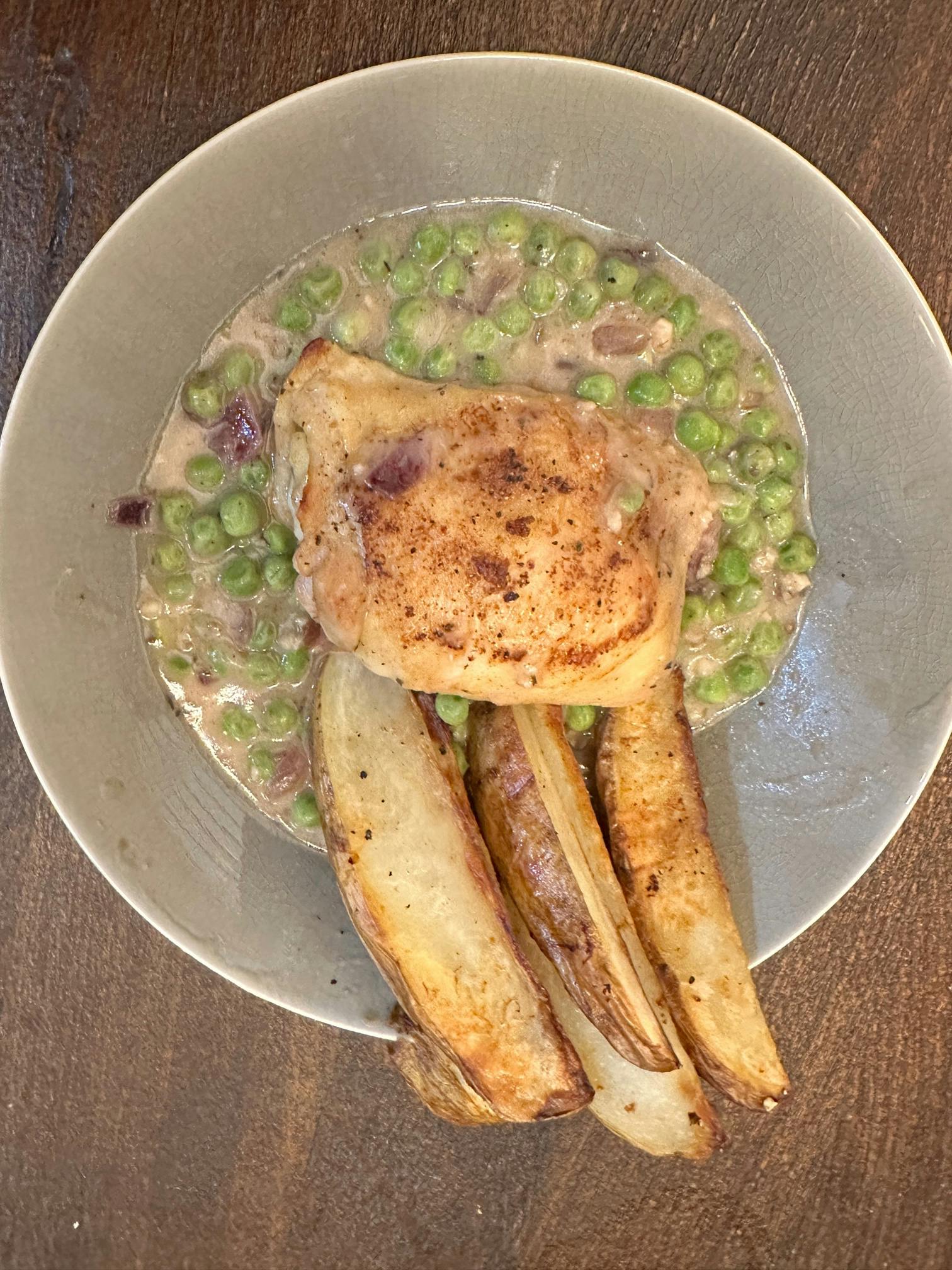 A plate of chicken Vesuvio with potatoes and peas