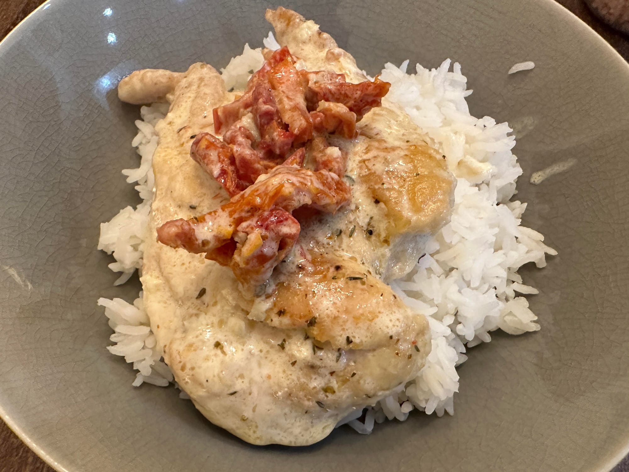 A bowl with Rice, Chicken and tomatoes on top.